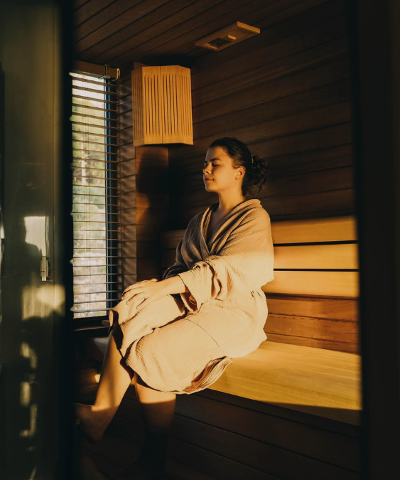 Woman in a robe relaxing confidently in a warmly lit sauna, embodying luxury wellness and self-care
